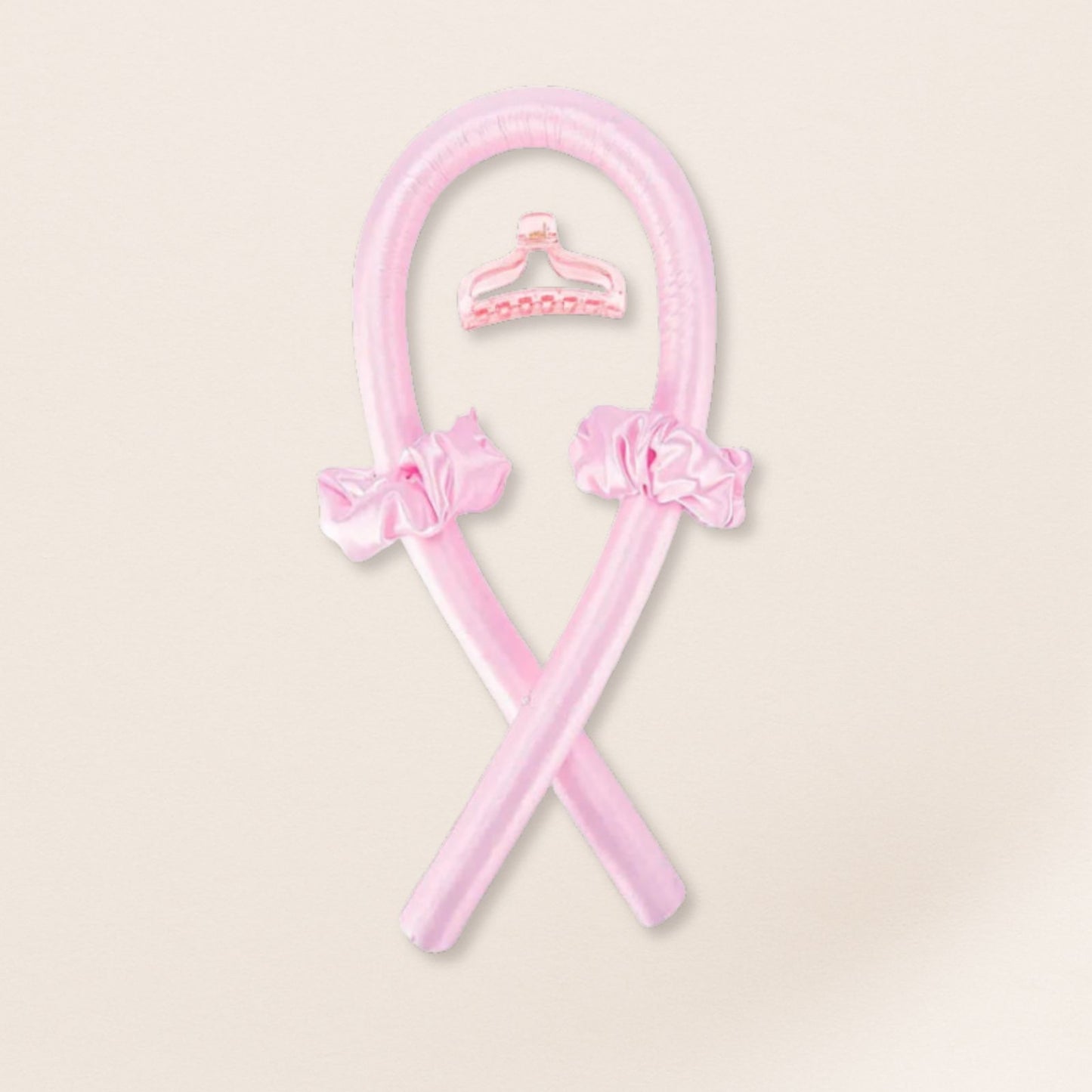 pink heatless curling set with matching satin scrunchies and a pink clip on a beige background