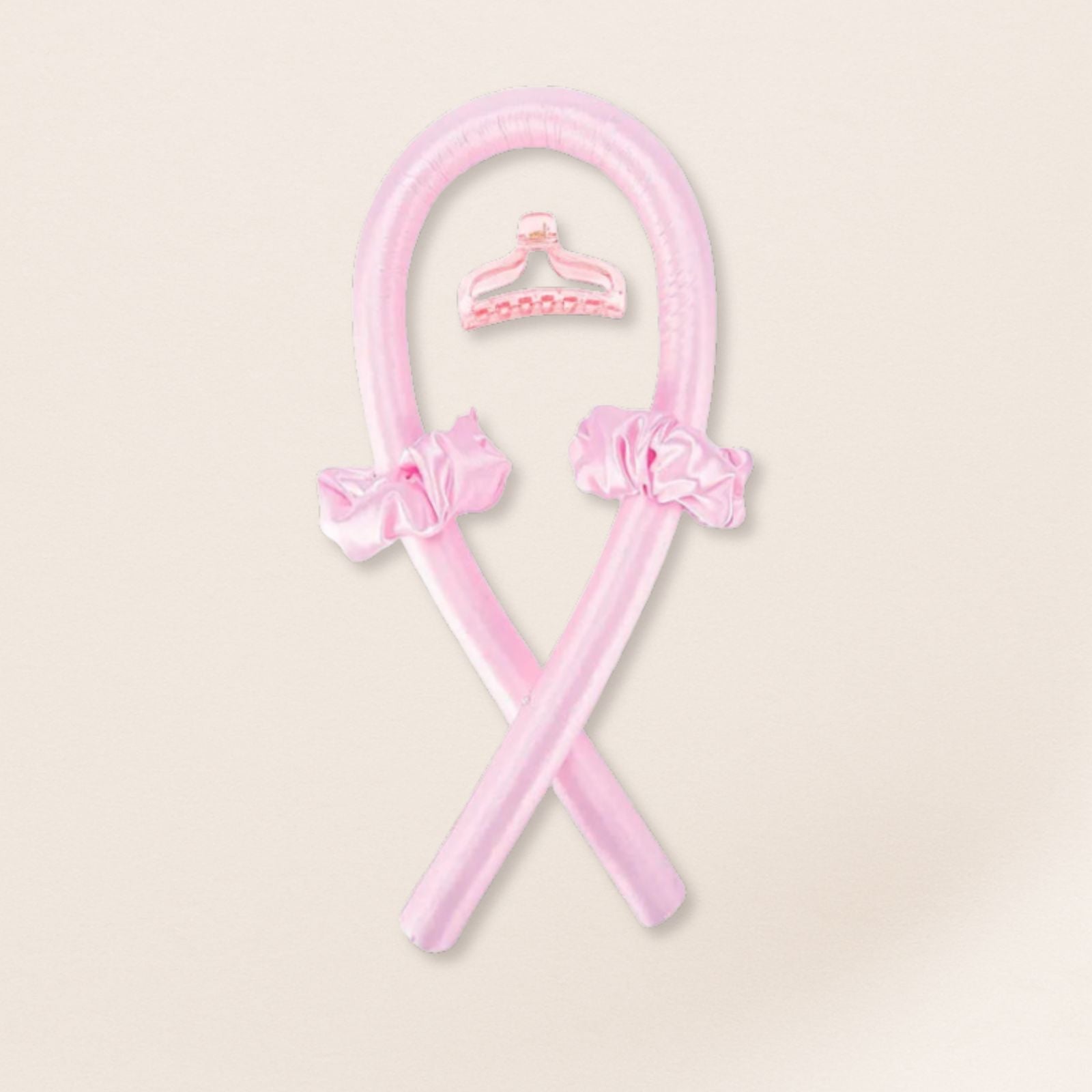 pink heatless curling set with matching satin scrunchies and a pink clip on a beige background
