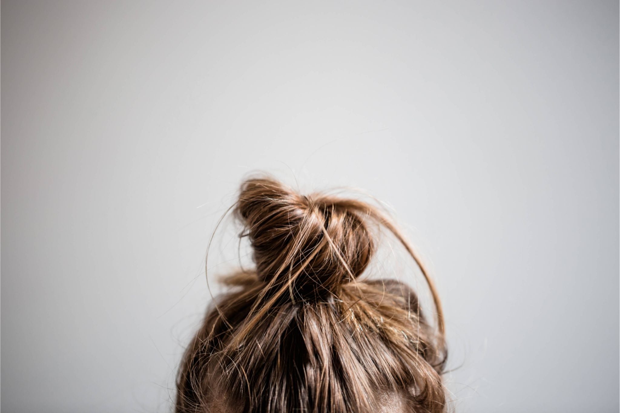 Close-up of a loose top bun hairstyle on fine brown hair, lightweight and natural.