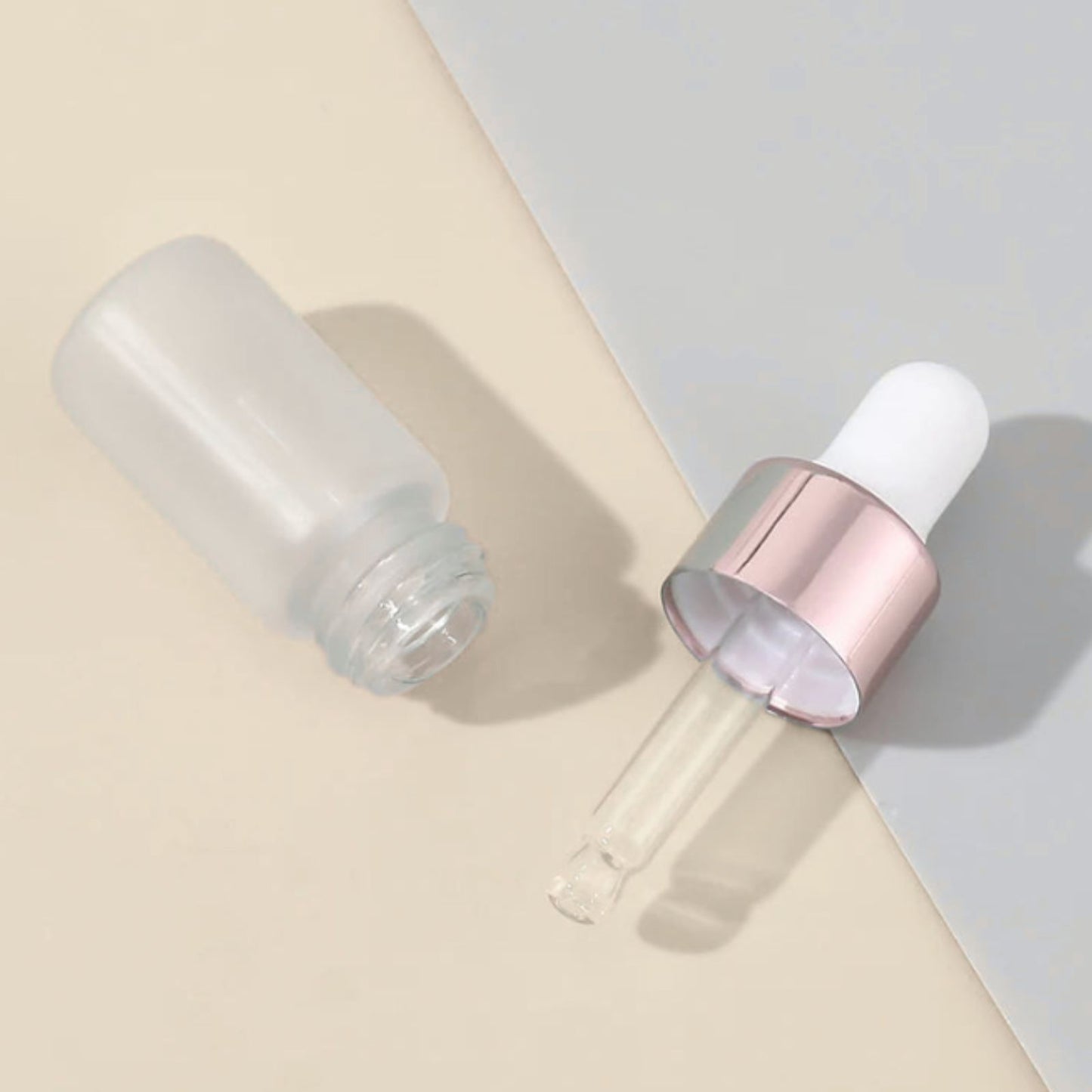 Clear dropper bottle on a beige and gray background