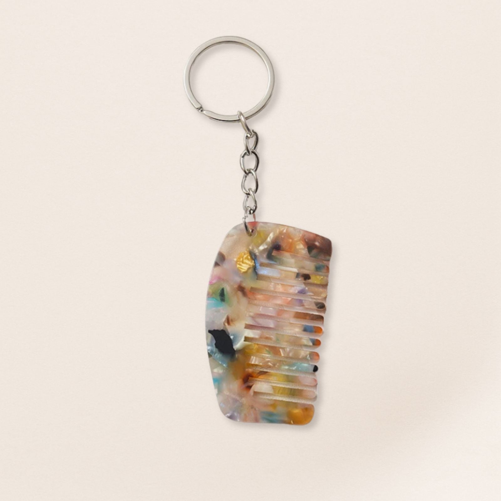 Colorful comb-shaped keychain on a beige background