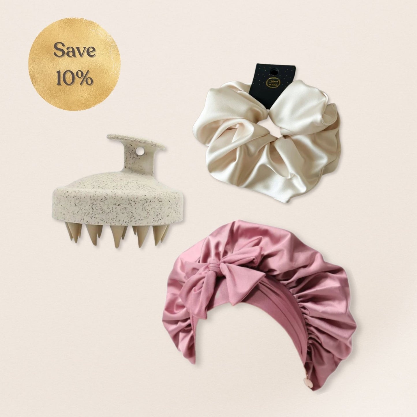 Set of hair care products including a scrubber, white scrunchie, and pink satin bonnet on a beige background.